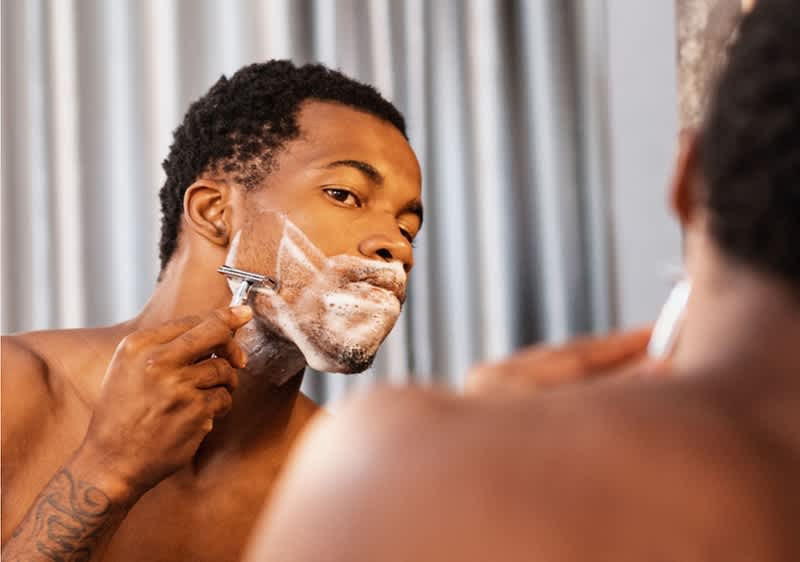 Bărbat ras în fața oglinzii cu fața blurată