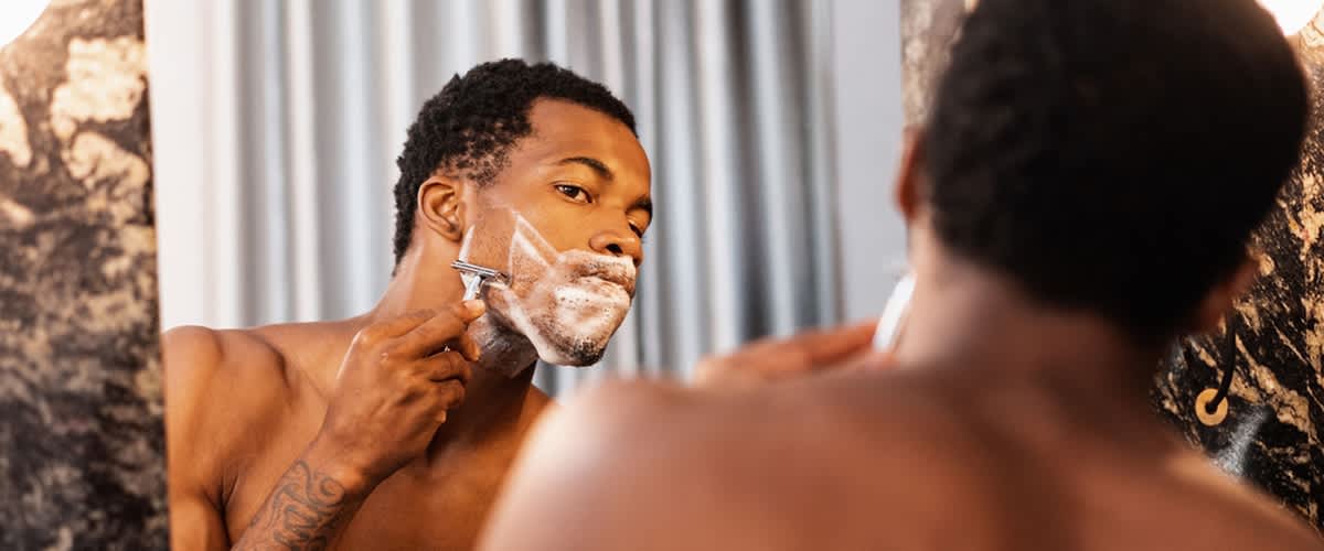 Bărbat ras în fața oglinzii cu fața blurată