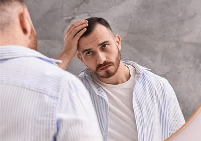 Bărbat în cămașă dungi verificându-și părul în oglindă