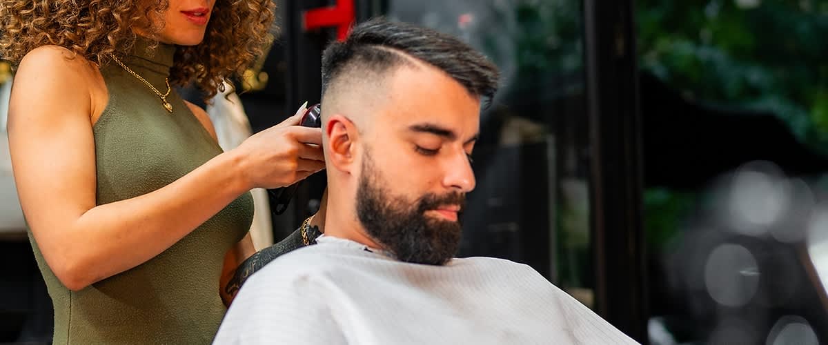 Persoană tunsă de frizer într-o frizerie