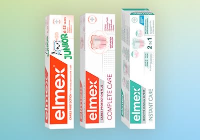 Trei cutii de pastă de dinți Elmex pe fundal colorat
