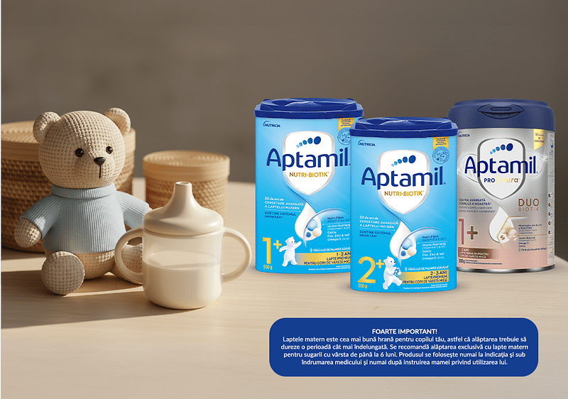 Trei cutii de lapte praf Aptamil lângă un ursuleț și o sticlă pentru bebeluși