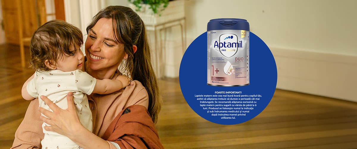 Cutie de lapte praf Aptamil și mamă ținând bebeluș în brațe