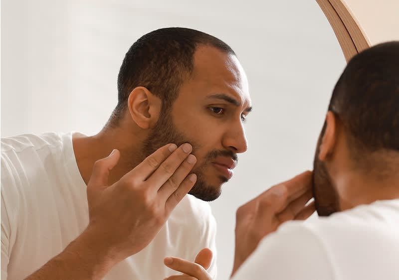 Bărbat verificându-și barba în oglindă