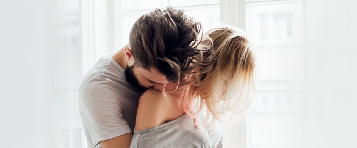 Cuplu îmbrățișat într-o cameră luminoasă