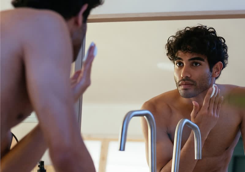 Cuvântul cheie principal: bărbat Bărbat aplicând cremă pe față în fața unei oglinzi