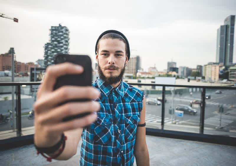 Persoană făcând un selfie pe o terasă urbană cu clădiri în fundal