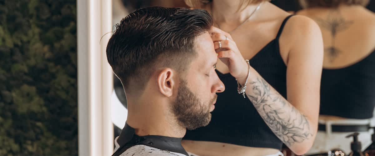 Client la frizerie cu tunsoare proaspătă și stilistă tatuată