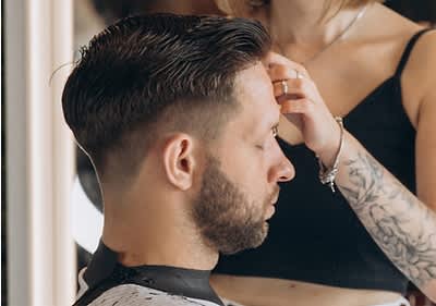 Client la frizerie cu tunsoare proaspătă și stilistă tatuată