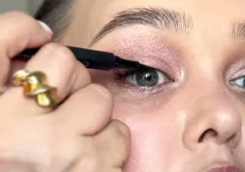 O mână ținând o bijuterie aurie