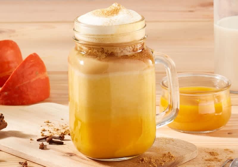 Latte de dovleac într-un borcan cu lapte și dovleac pe masă.