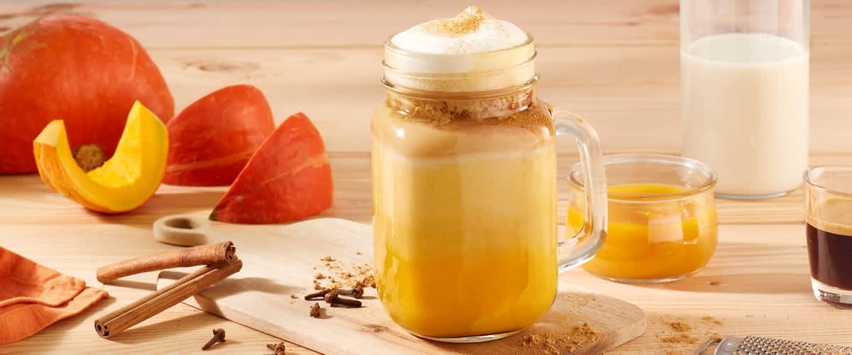 Latte de dovleac într-un borcan cu lapte și dovleac pe masă.