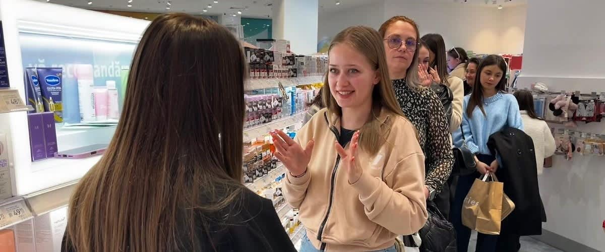 Tânără explicând ceva vânzătoarei într-o coadă la magazin cosmetic
