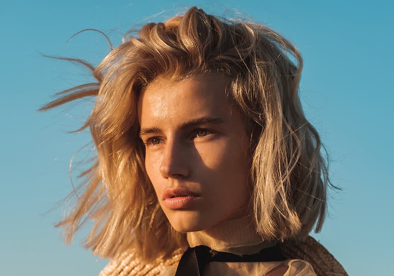 Fată cu păr blond pe fundal de cer senin