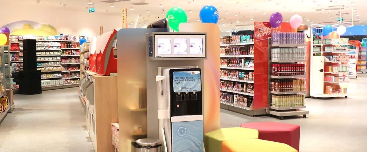 Mașină de înghețată soft self-service într-un supermarket cu rafturi și baloane colorate în fundal