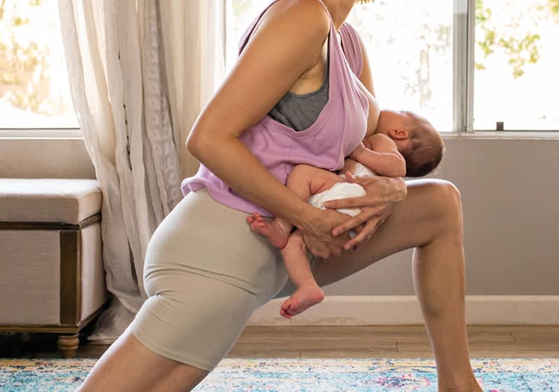 Mamă care alăptează bebeluș în poziție de exercițiu acasă