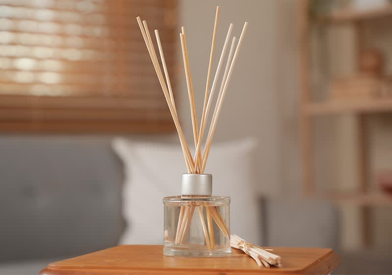 Difuzor aromatic din sticlă cu bețișoare parfumate pe masă în interior