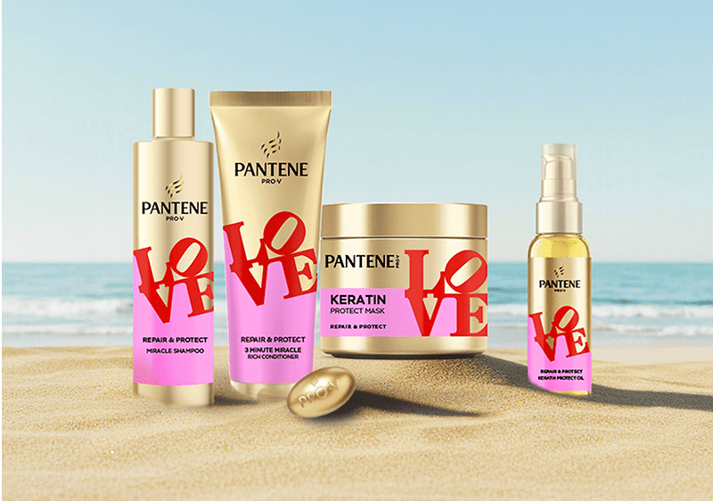 Produse Pantene LOVE pe nisip cu plajă și mare în fundal