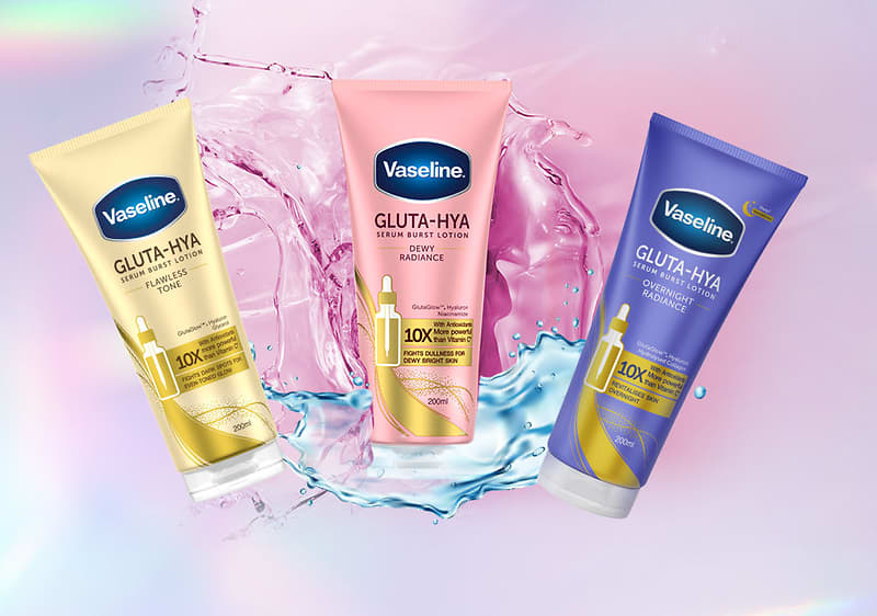 Vaseline Gluta‑HYA trei tuburi de loțiune pe fundal roz cu stropi de apă