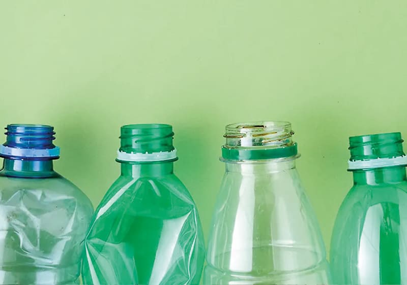 Sticle din plastic goale aliniate pe fundal verde