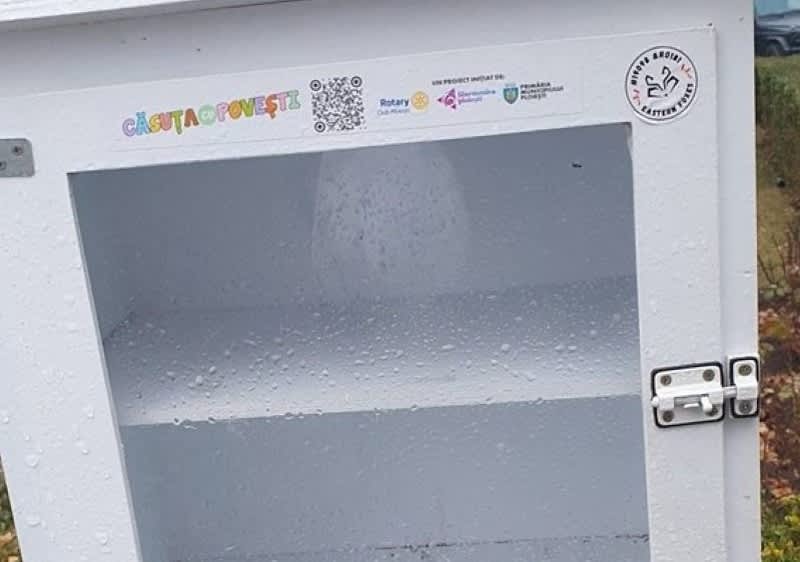 Căsuță de povești albă cu geam și etajere goale într-un spațiu exterior