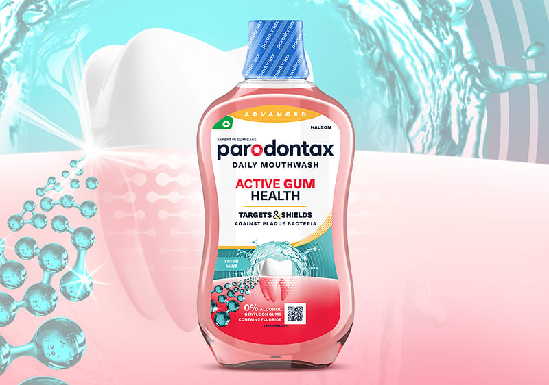 Sticlă de apă de gură Parodontax Active Gum Health în prim-plan cu dinte și stropi de apă în fundal
