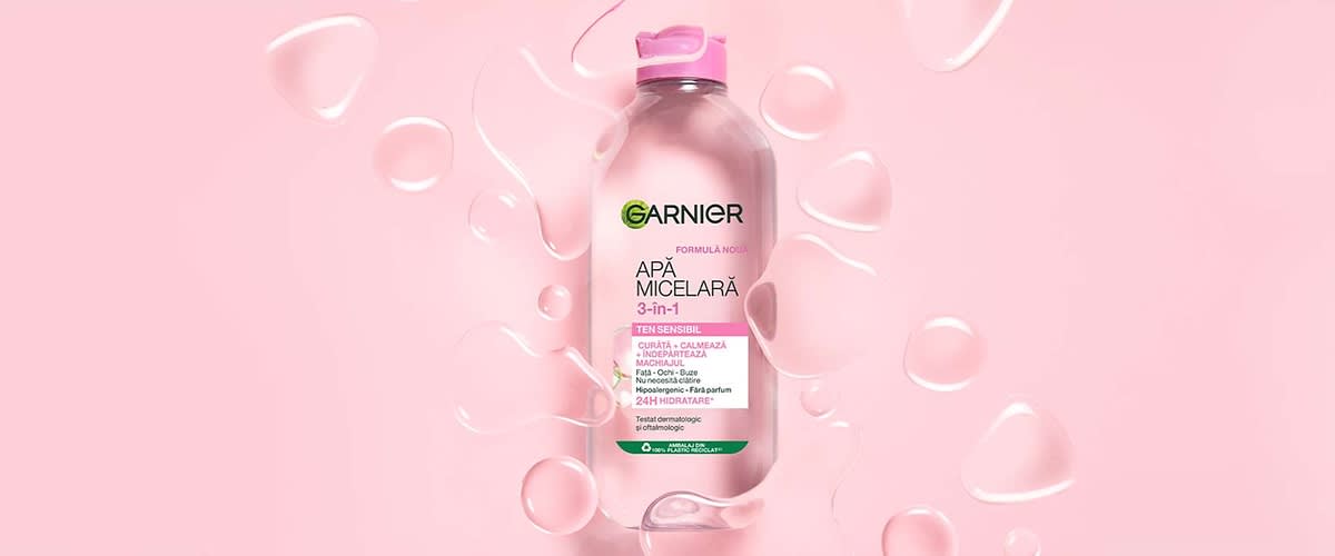 Apă micelară Garnier 3-în-1 pentru ten sensibil pe fundal roz cu picături de apă