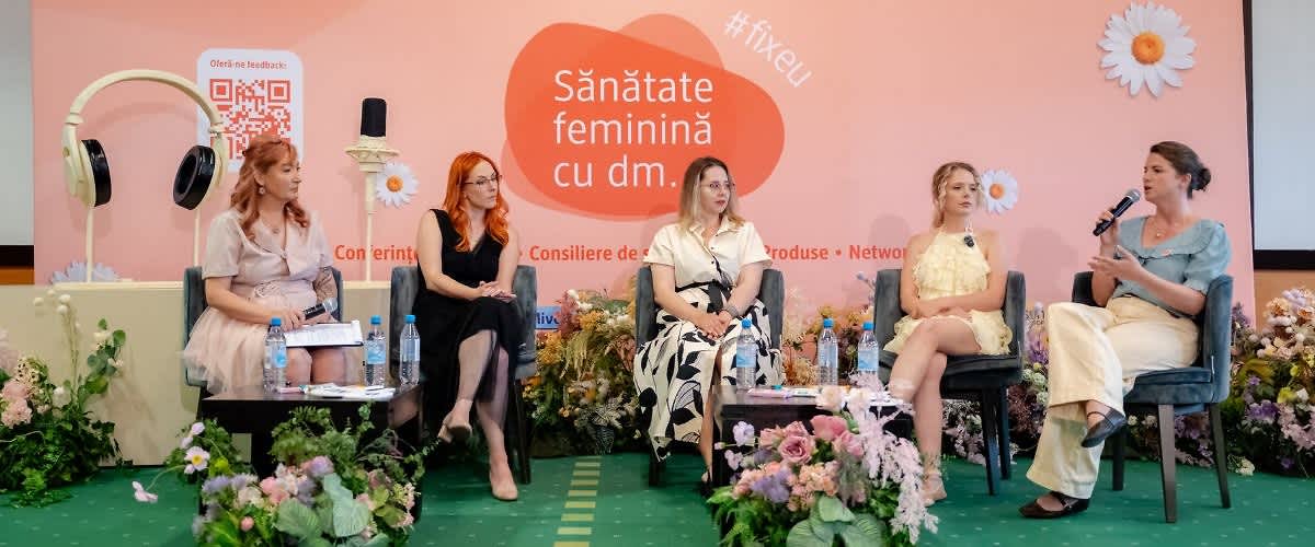 Sănătate feminină cu dm eveniment cu femei pe scenă în discuție și aranjamente florale