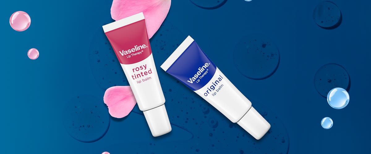 Două tuburi de balsam de buze Vaseline roz rosy tinted și albastru original pe fundal albastru cu petale