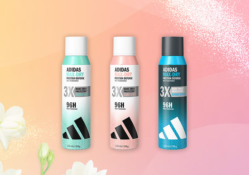 Trei spray-uri deodorante Adidas Max Dry aliniate pe fundal roz-portocaliu; sticla din stânga verde deschis cu capac alb, cea din mijloc roz pal cu capac alb și cea din dreapta albastru închis cu capac negru, fiecare etichetă arată „ADIDAS MAX-DRY”, „3X” și „96H”, logo-ul Adidas în partea de jos