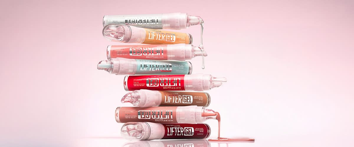 Șapte tuburi transparente de gel LIFTER GEL stivuite orizontal, fiecare cu conținut colorat diferit (roz pal, portocaliu, corai, turcoaz, roșu, maro, roșu închis), picurând gel la capete pe un fundal roz deschis