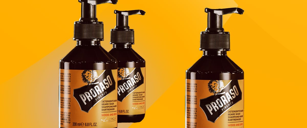 Trei sticle cu pompă PRORASO 200 ml, ambalaj maro cu etichetă galbenă și siglă leu, text „PRORASO” și „WOOD AND PEAT”, produs pentru spălare și îngrijire a bărbii, fundal galben în degradeu