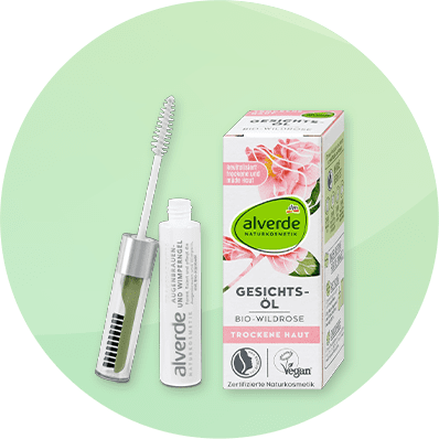 Eine weiße Verpackung mit der Aufschrift „alverde Gesichtsöl Bio-Wildrose“ und ein geöffneter Flakon mit Bürste auf grünem Hintergrund