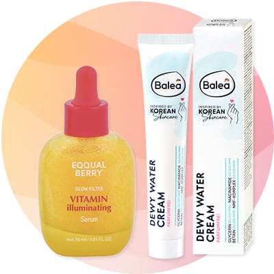 Žlté sérum v priehľadnej fľaštičke s červeným aplikátorom s nápisom „EQQUAL BERRY VITAMIN illuminating Serum 30 ml“ vedľa bieleho tubusu a škatuľky Balea s modrým prvkom a nápisom „DEWY WATER CREAM“ a logom Balea