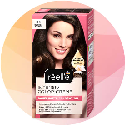 Krabička farby na vlasy réell'e Intensiv Color Creme odtieň 3.0 Dunkel Braun s obrázkom usmievajúcej ženy, čierno-hnedými vlasmi, nápismi „INTENSIV COLOR CREME“ a „DAUERHAFTE COLORATION“ a ikonkou mandle a textom „Farb-Glanzkur mit Mandelöl“
