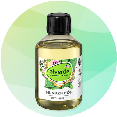 Priehľadná fľaša s čiernym uzáverom obsahujúca žltozelený olej, na etikete zelené oválne logo „alverde NATURKOSMETIK“, nápis „MUNDZIEHÖL“ a podnápis „BIO-MINZE“, v pozadí jemný zelený kruh