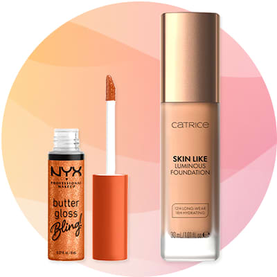 Lesk na pery NYX Professional Makeup „butter gloss bling“ v malom priehľadnom obale s oranžovo-žiarivým leskom a odnímateľným aplikátorom vedľa zlatobéžového flakónu make-upu Catrice „Skin Like Luminous Foundation“ s čiernym logom a textom „12H long-wear 18H hydrating“ na spodnej časti flakónu