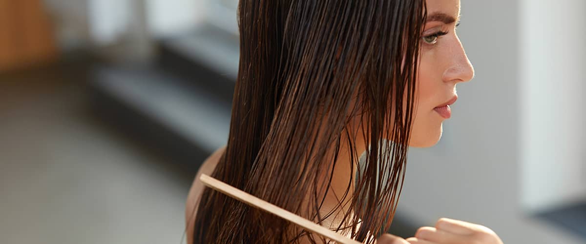 Žena si češe mokré vlasy