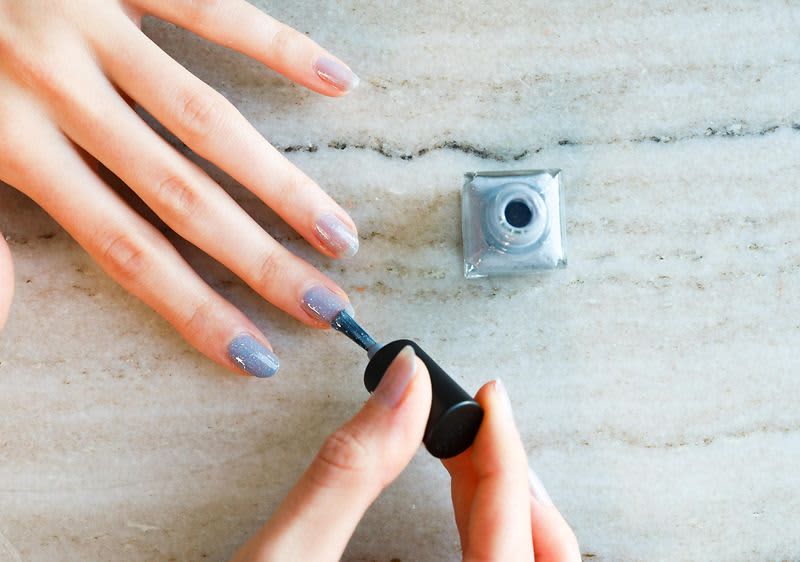 Nanášanie laku sivej farby na nechty.