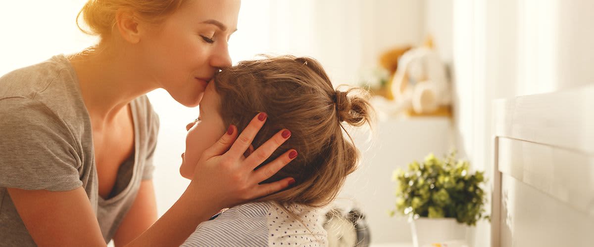 Mama bozkáva dcéru na čelo.