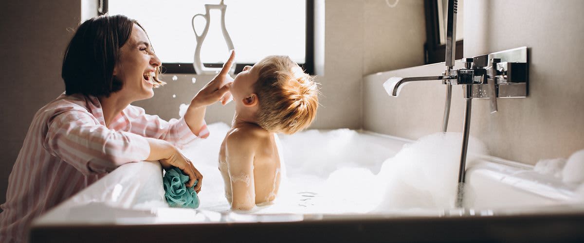 Mama lacht mit Sohn in der Badewanne