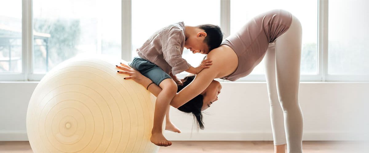 žena cvičiaca na fitlopte s chlapčekom