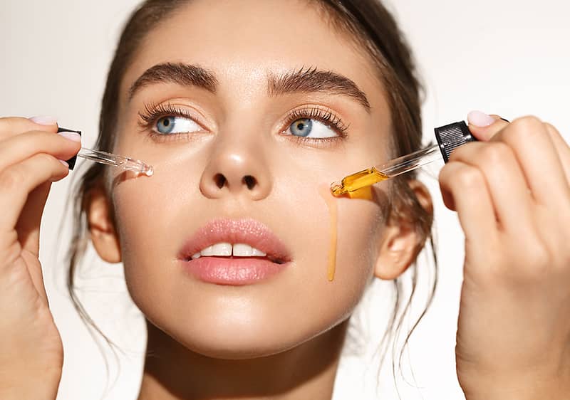 Žena si nanáša kvapkadlom vitamín C na pleť