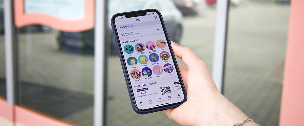 Ruka s mobilom s aplikáciou Moja dm-App