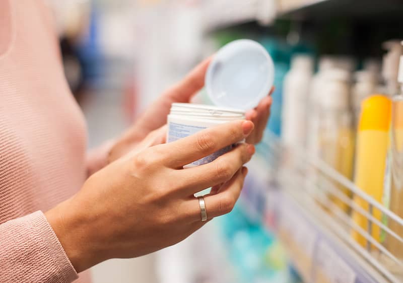 Ženská ruka drží otvorený téglik s krémom