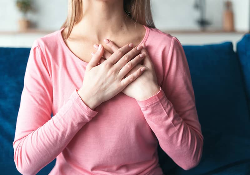 Žena s rukami pritisnutými k svojmu srdcu.