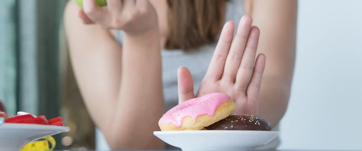 žena s jablkom v ruke odmieta donuty