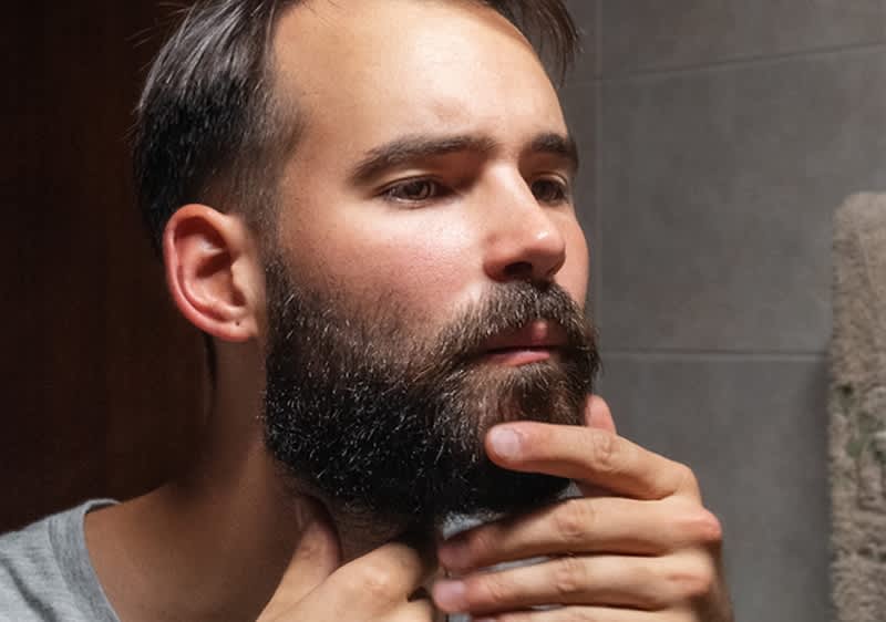 muž s bradou pozerajúci do zrkadla