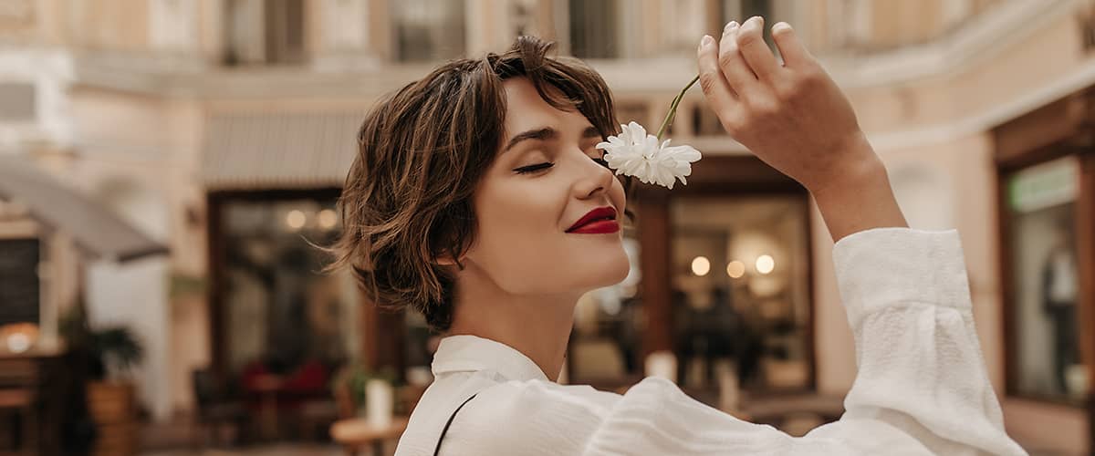 žena v meste ovoniava kvet