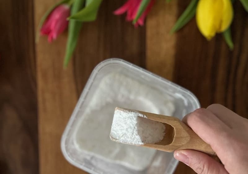 prací prostriedok na drevenej lyžici nabratý z plastovej dózy